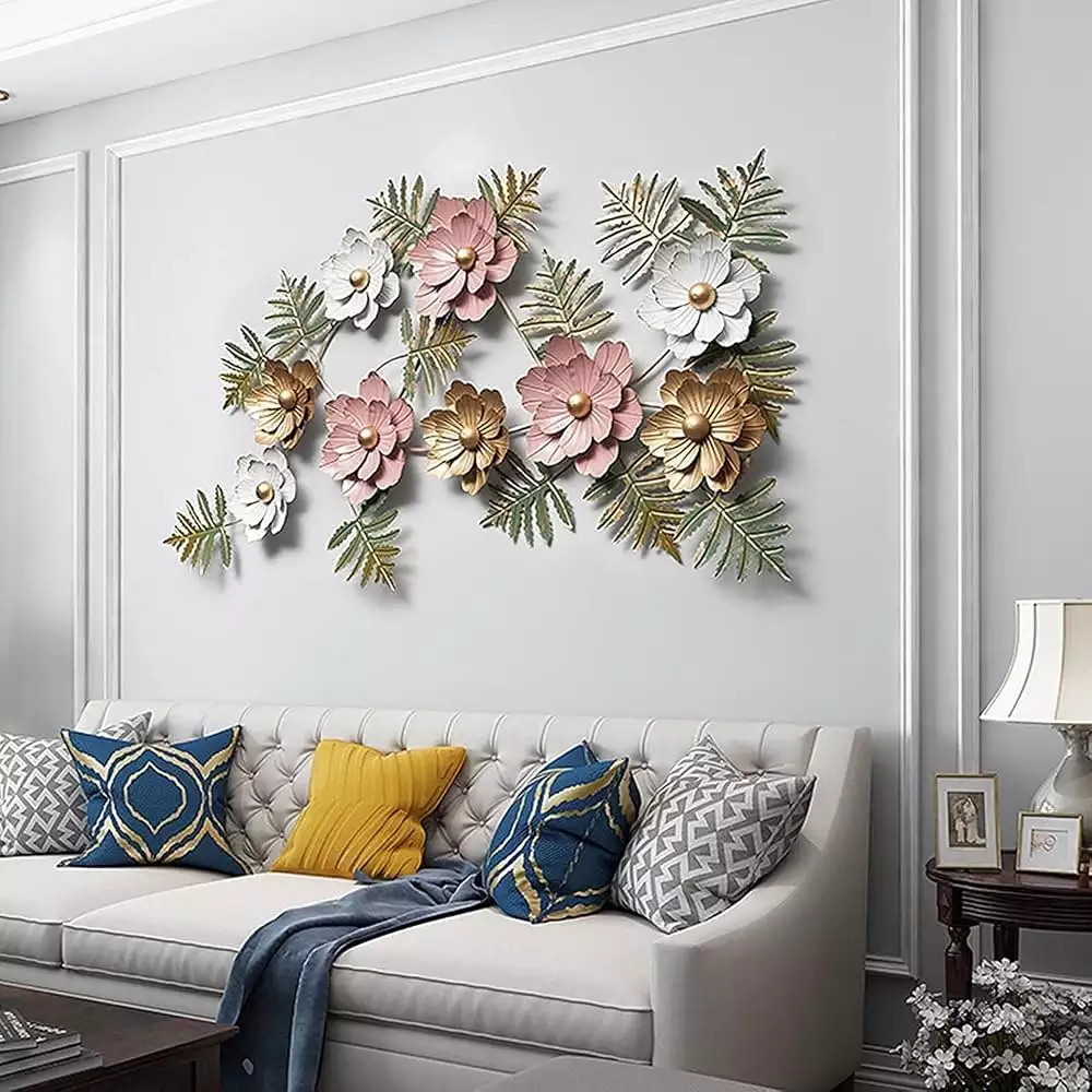 3D metal flower Indian wall decor piece in pink, white, and gold above a tufted living room sofa