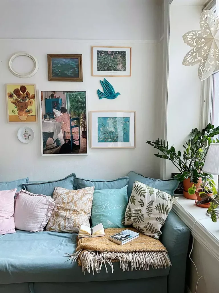 A blue sofa with patterned pillows under a framed art print gallery wall and a teal bird for easy aesthetic DIY room decor