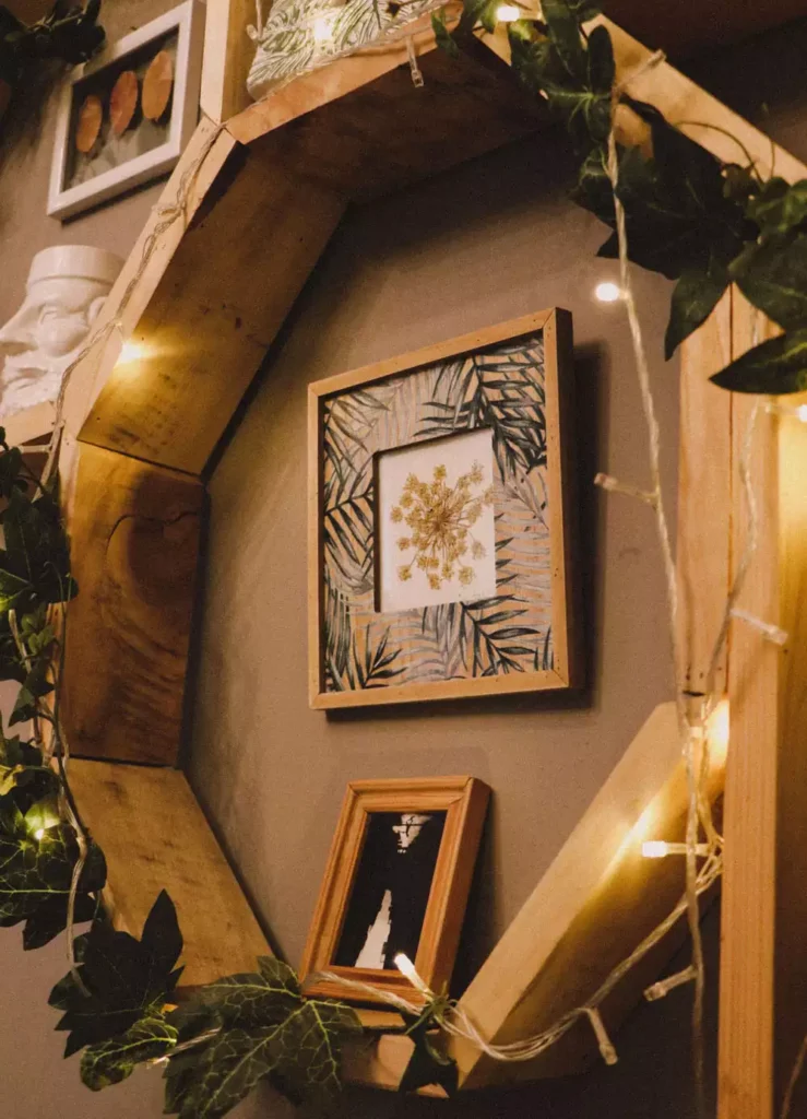 A giant wooden octagon frame wrapped in fairy lights and ivy, a rustic wall decor idea around a framed botanical print