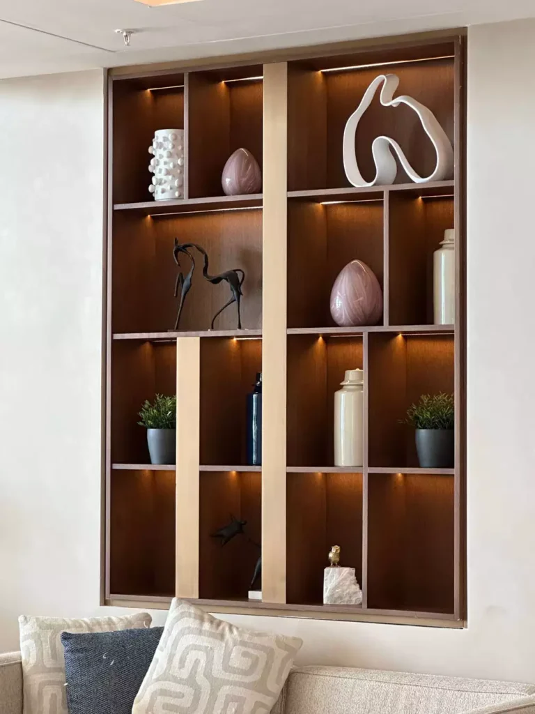 Backlit built-in shelving nook with ceramic vases and sculptures, elegant wall decor for a lounge area