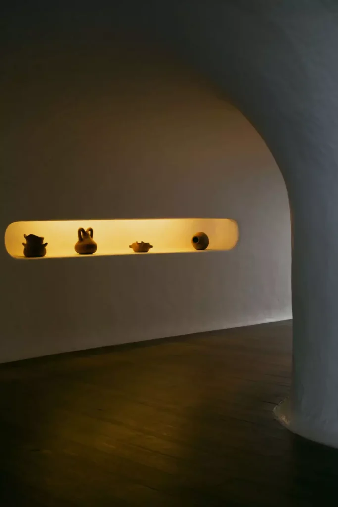 Backlit Wall Arch Niche Displaying Small Clay Pots In A Dim Room