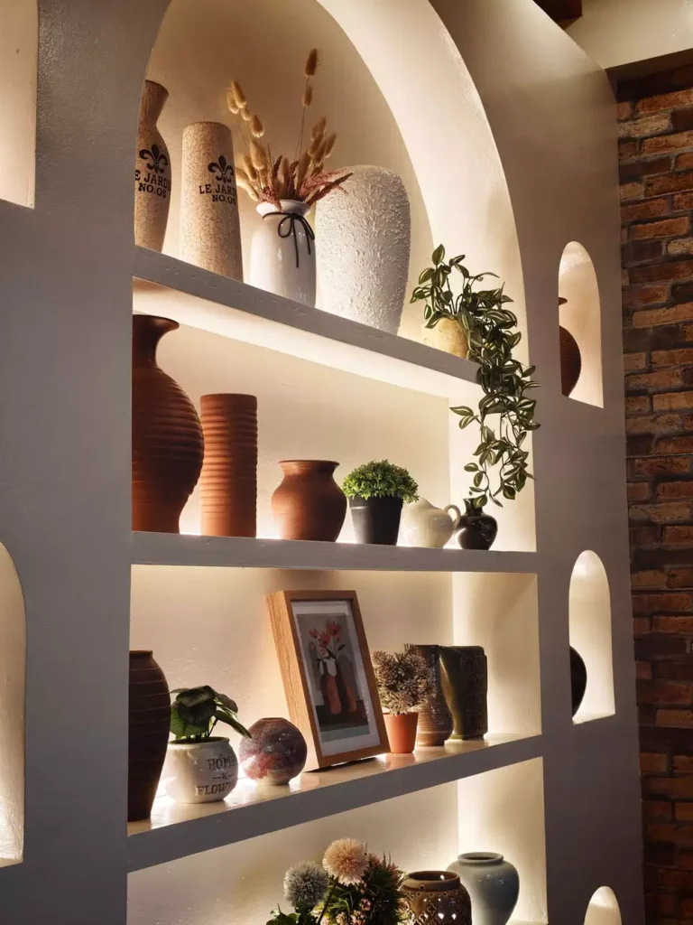 Backlit Wall Arch Shelving Filled With Pottery And Trailing Plants