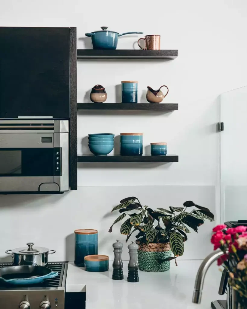 Black Floating Shelves With Teal Canisters Make Simple Kitchen Wall Decor Against A White Wall