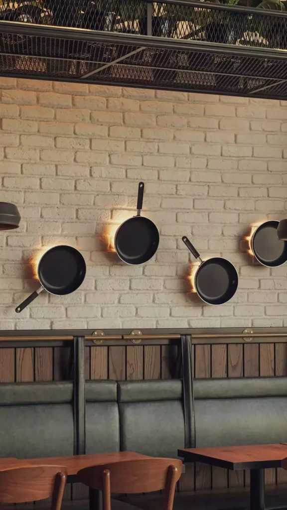 Black Frying Pans Mounted On A White Brick Wall Create Rustic Kitchen Wall Decor With Warm Glow