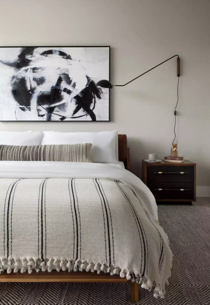Black and white abstract framed art as modern over the bed wall decor with a wall sconce