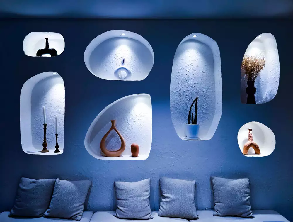 Blue Wall With Sculpted Wall Arches Holding Candlesticks And Vases