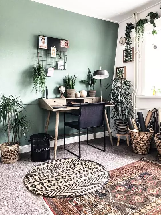 Boho green wall office with hanging plants and a mid-century wood desk