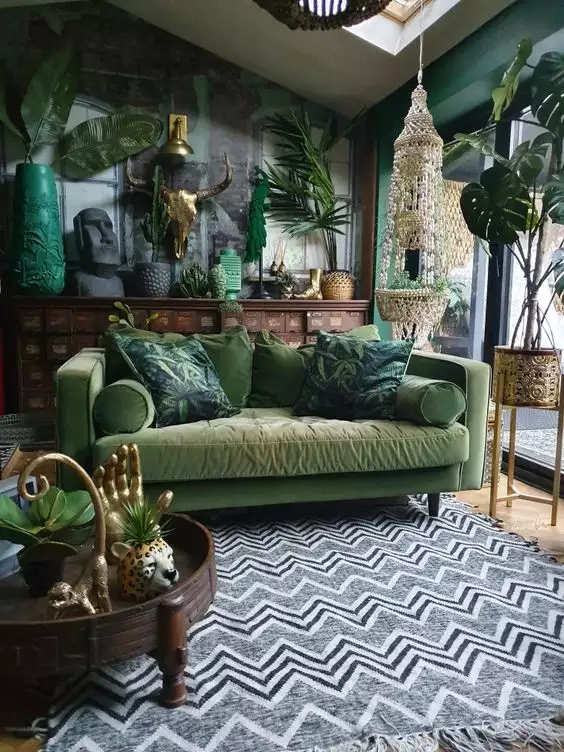 Boho living room with olive green walls, velvet sofa, plants, and a zigzag rug