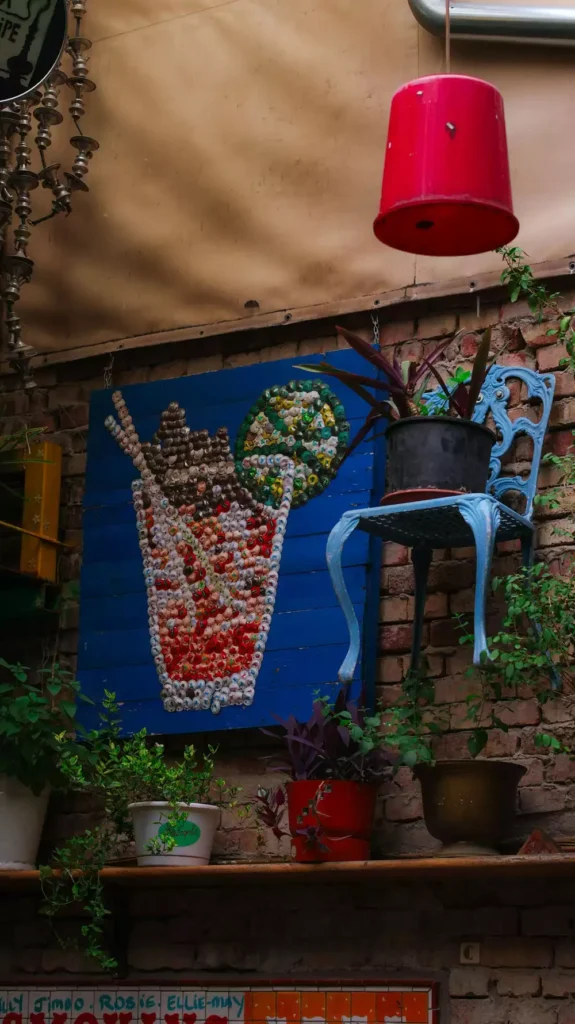 Bottle Cap Mosaic Art And Potted Plants On An Outdoor Brick Wall