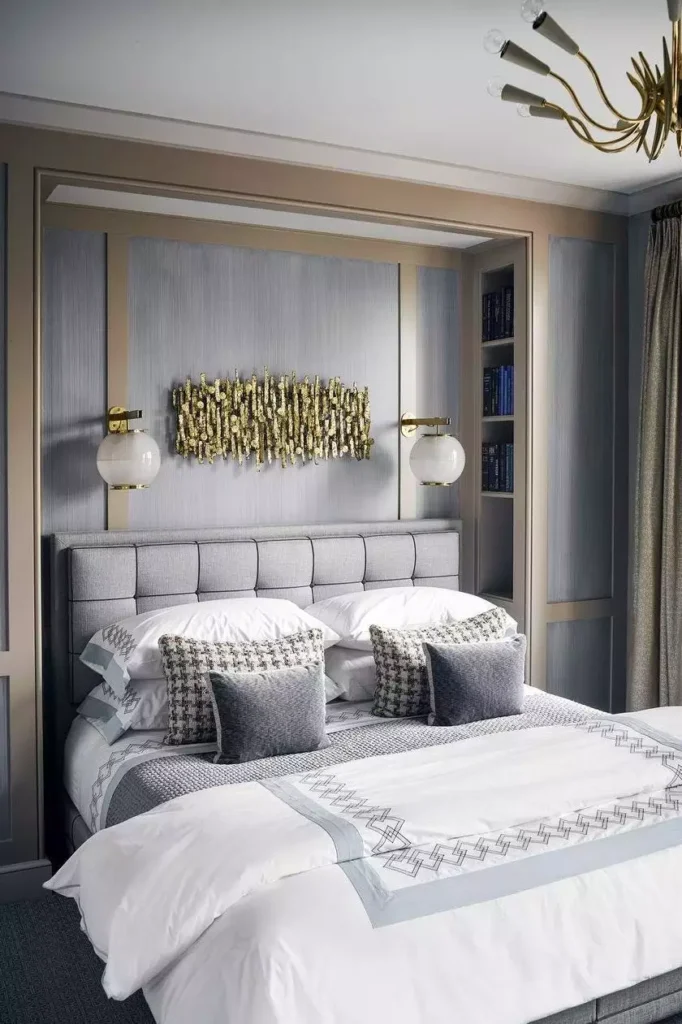 Brass sconce lighting flanking a gold metal wall sculpture as glam over the bed wall decor