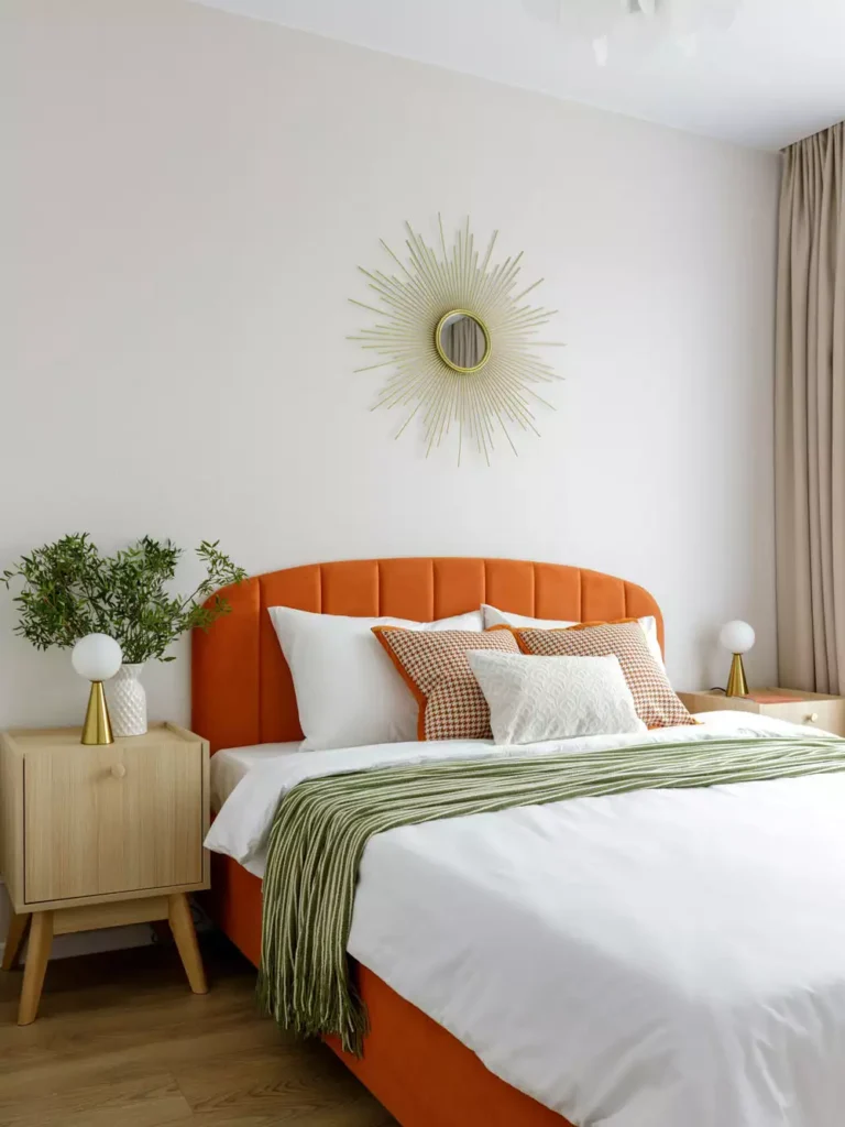 Brass sunburst mirror as chic over the bed wall decor above an orange headboard