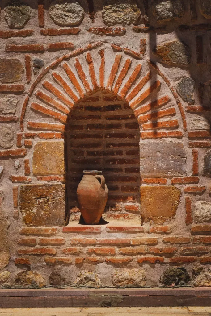 Brick Wall Arch With A Terracotta Jug On An Old Stone Facade