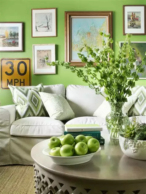 Bright lime green walls behind a white sofa, mixed frames, and green apples