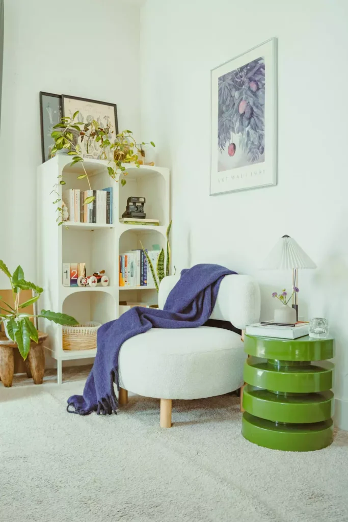 Bright living room corner decor with a framed wall print, arched white bookcase, boucle chair, and green side table