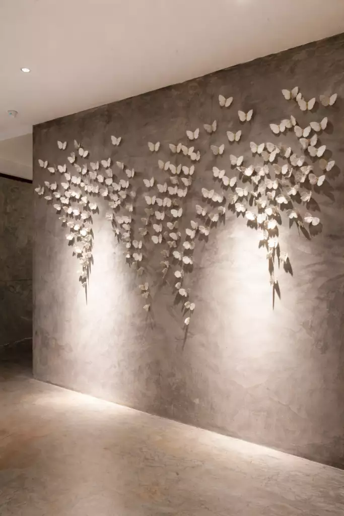 Cascading white Butterfly Wall installation dripping down a moody plaster hallway