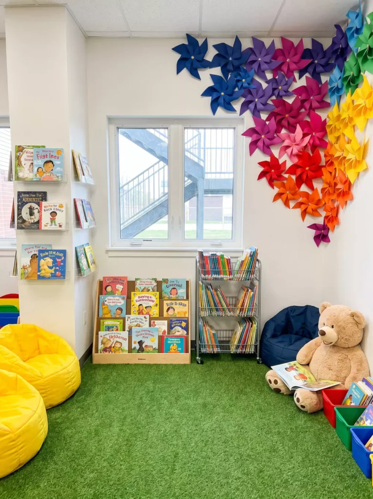 Classroom Reading Corner Library With A Rainbow Pinwheel Wall And Green Turf Flooring