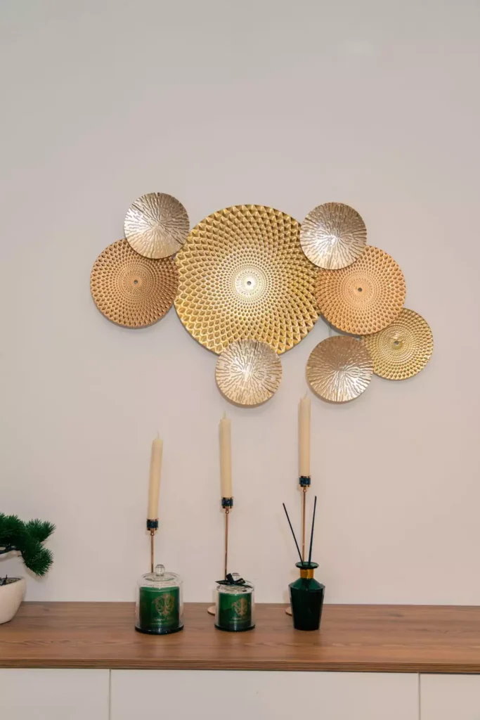 Cluster of textured gold discs arranged as wall decor above a console with candles and incense