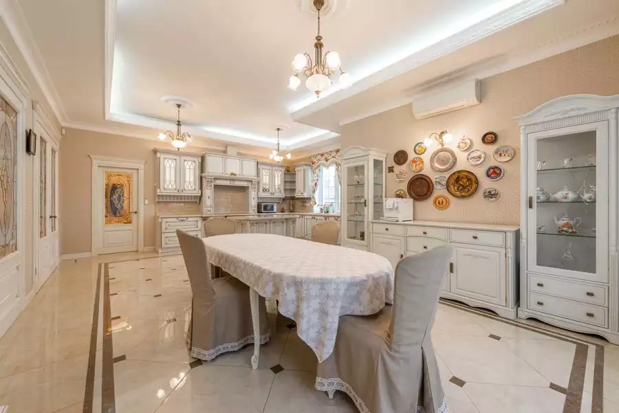 Colorful decorative plates hung on a beige wall create classic Dining Wall Decor beside a white china cabinet in a spacious dining room