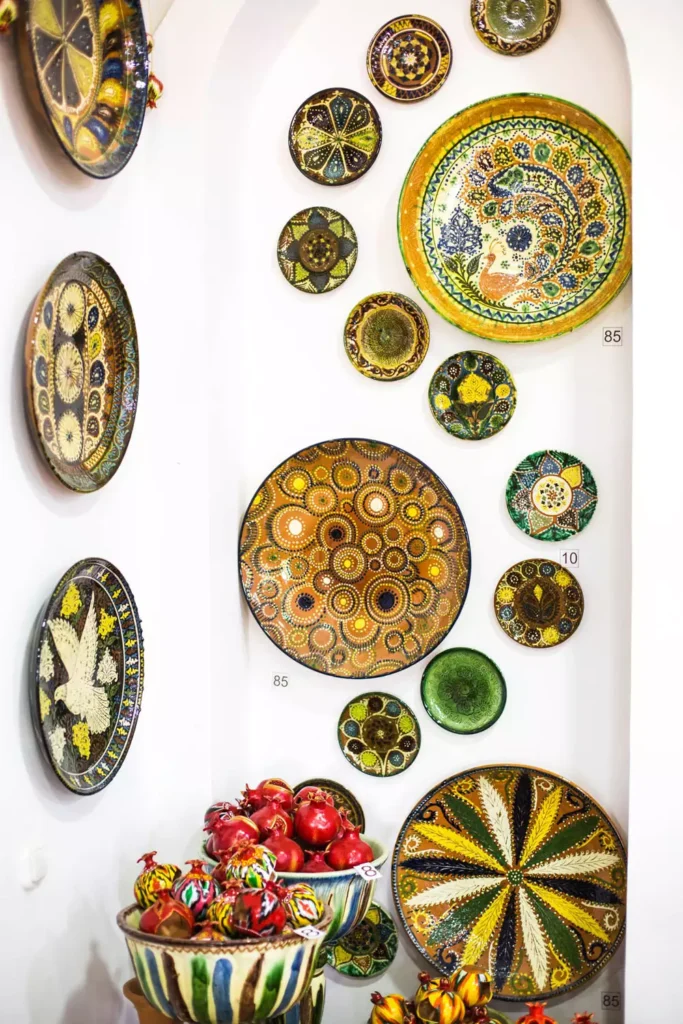 Colorful hand-painted plate wall decor with geometric and floral patterns displayed in an archway
