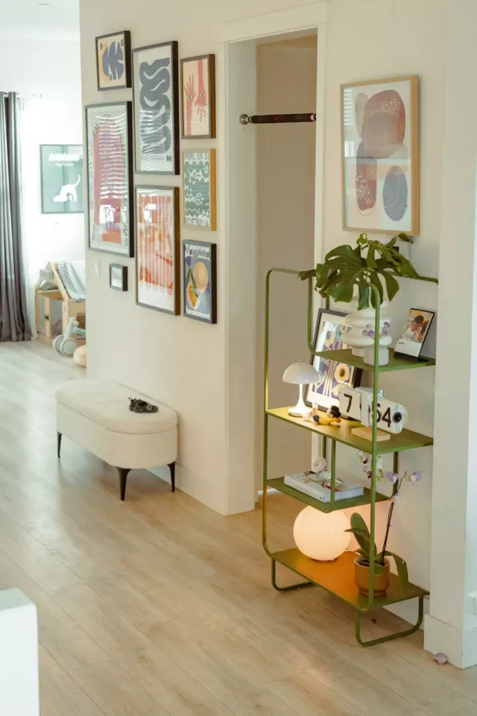 Colorful entryway room decor with abstract gallery wall, green metal shelf and monstera plant