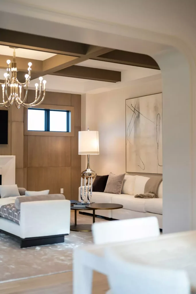 Contemporary tan wall living room with wood paneling, a crystal chandelier, and cream sofas