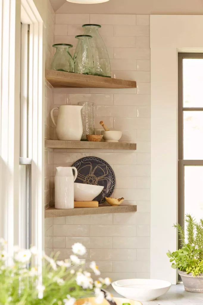 Corner kitchen wall shelves with glass bottles, pitchers, and a blue plate