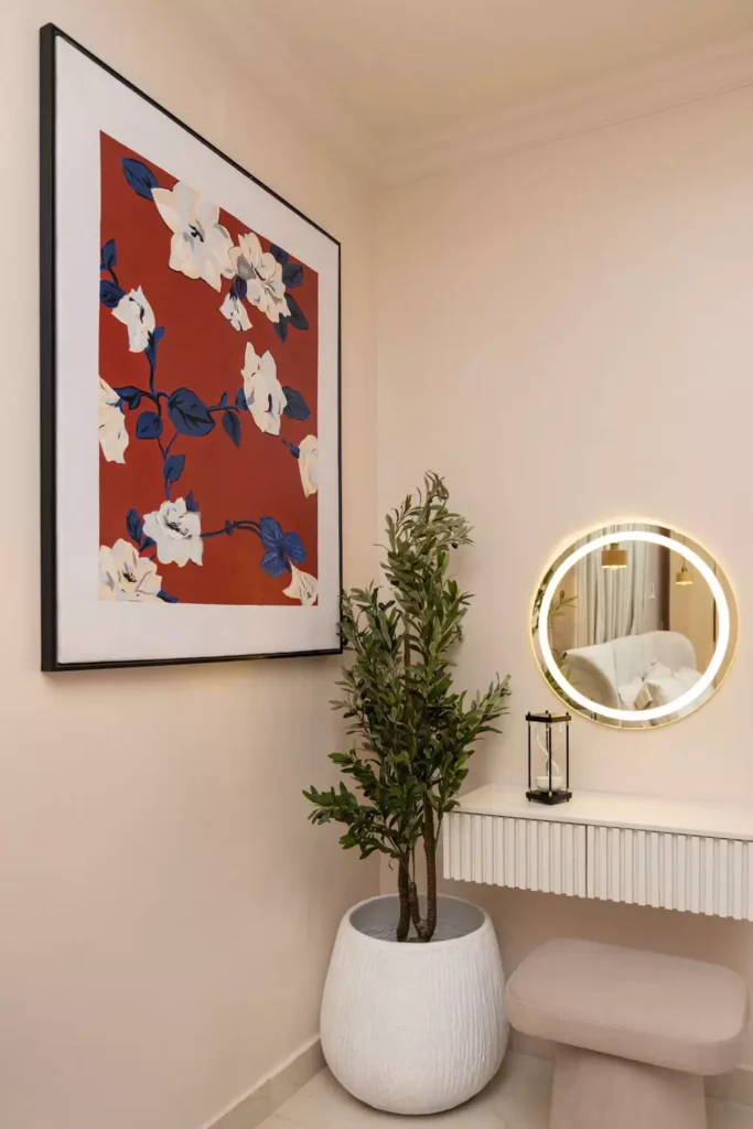 Corner wall art decor with a large floral canvas, potted tree, and round LED vanity mirror