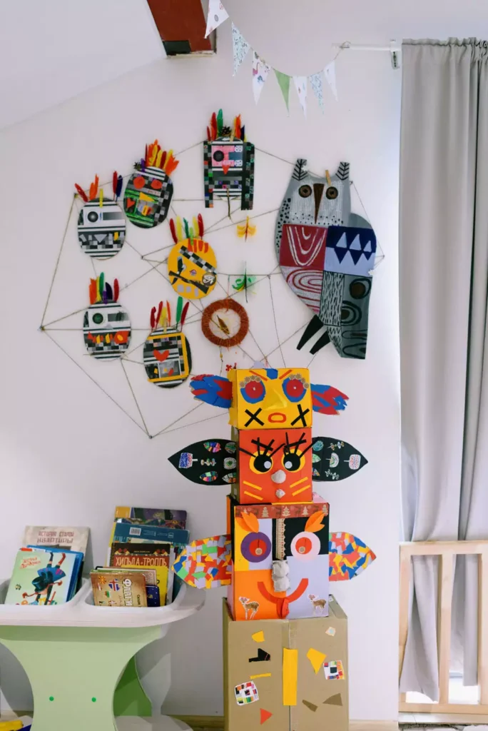 DIY feathered masks strung in a web pattern beside an owl mask, playful wall decor in a kid's room