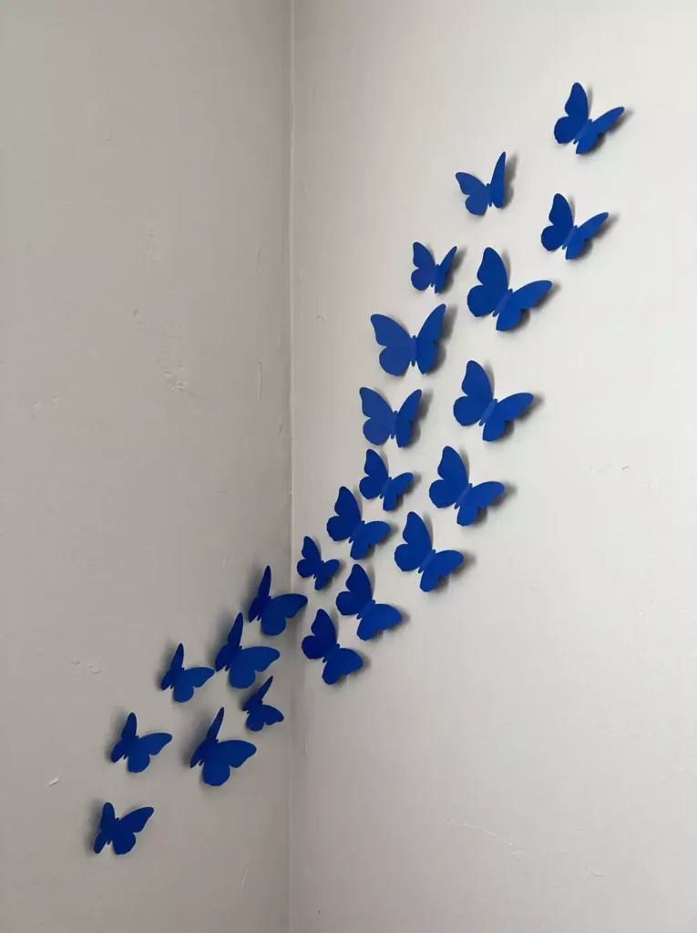 DIY corner wall decor with blue paper butterflies arranged diagonally on white corner wall
