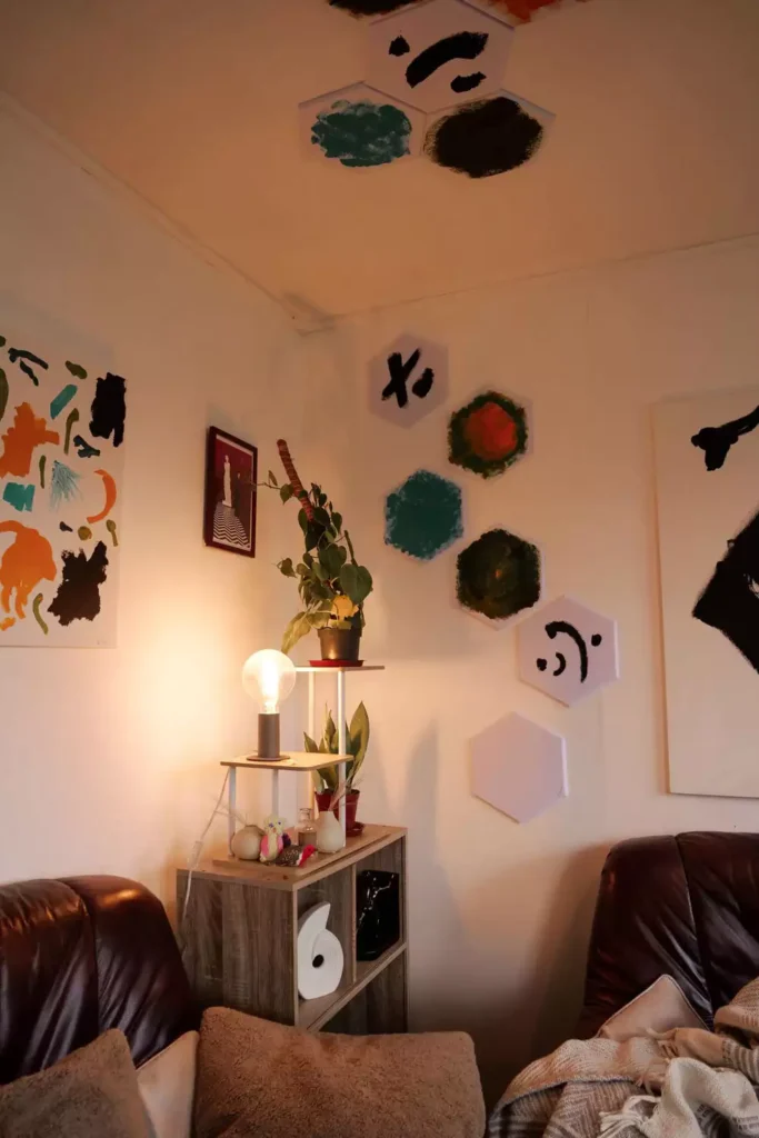 DIY corner wall decor with hand painted hexagon canvas art above brown leather sofas with floor lamp