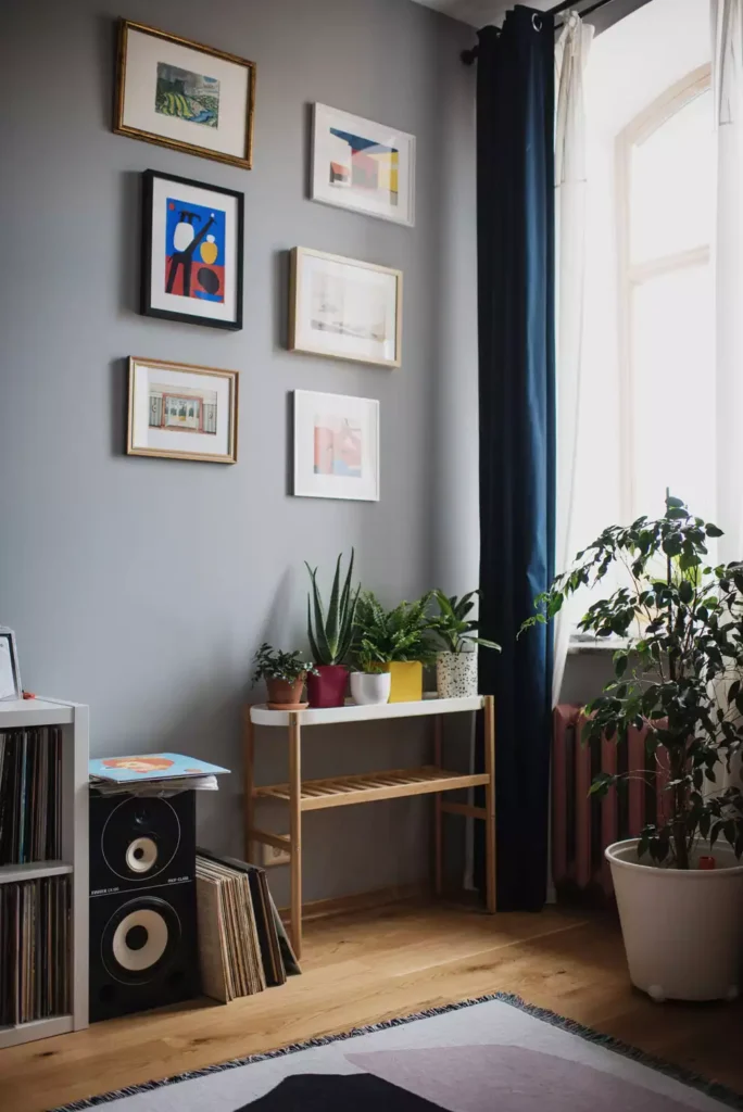 DIY corner wall decor with minimalist black framed gallery wall in gray corner with plant stand and tripod lamp