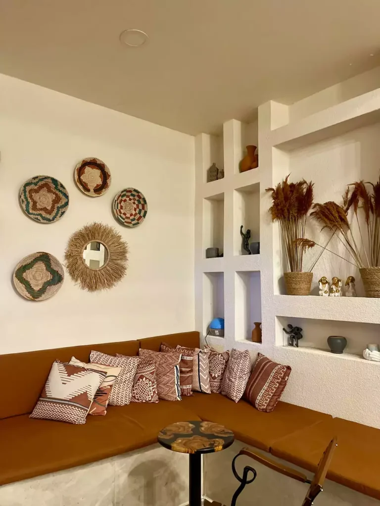 DIY corner wall decor with woven basket plates and raffia sunburst mirror above terracotta banquette seating