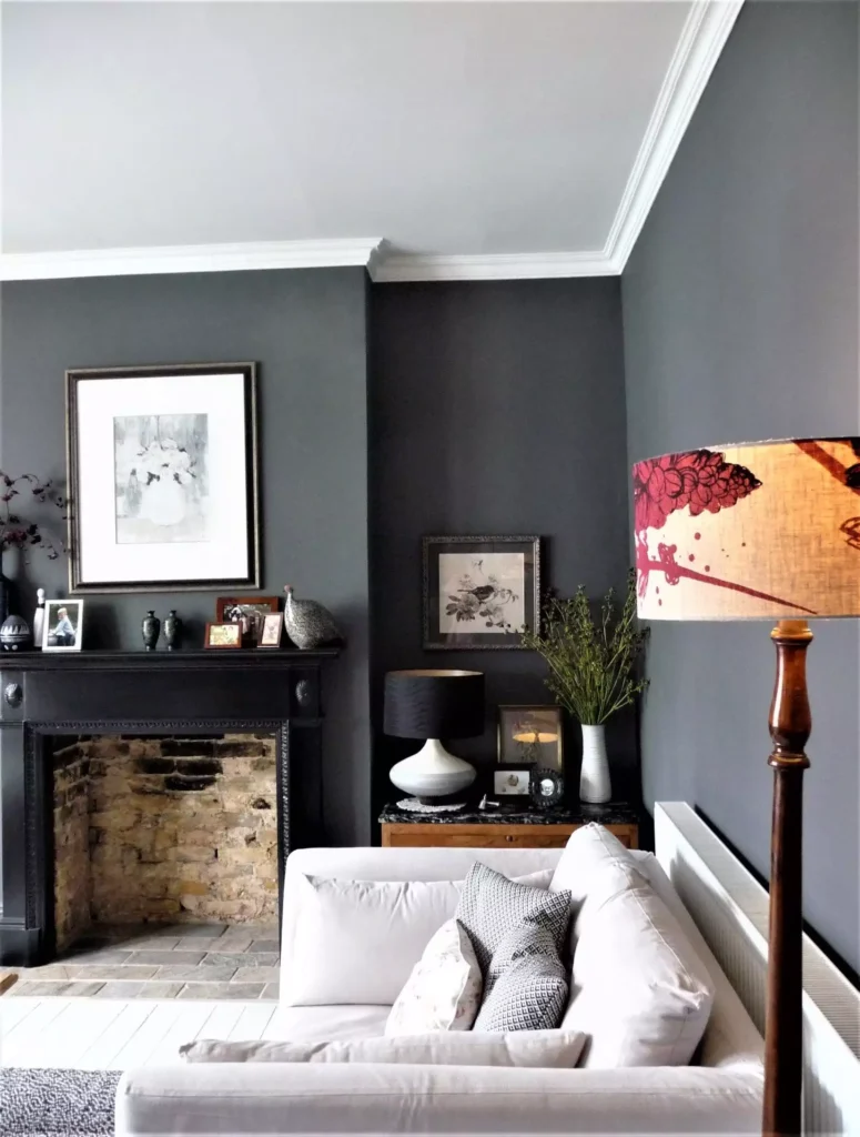 Dark grey living room walls with vintage fireplace, gallery frames and patterned lamp shade