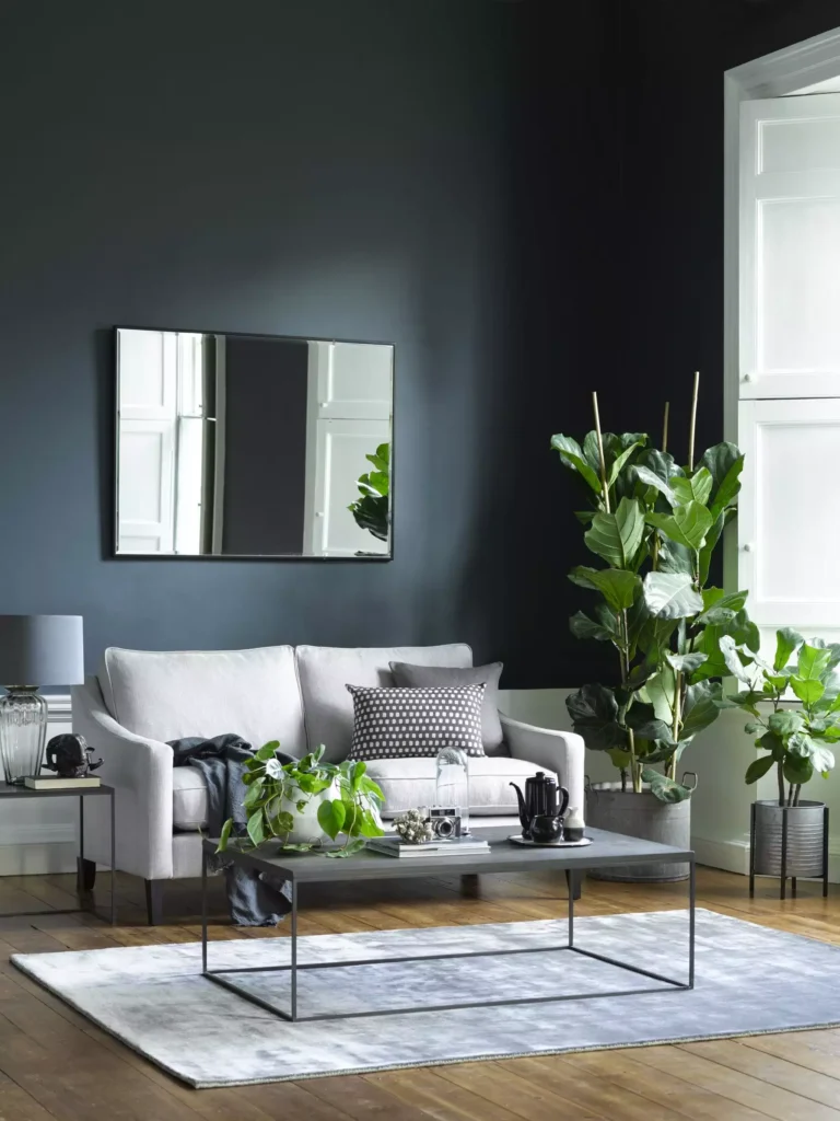 Dark slate grey living room wall with mirror, beige sofa and patterned cushion room decor idea for grey walls