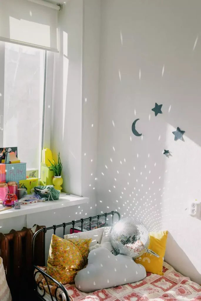 Disco ball scattering light spots beside moon and star wall decals, playful wall decor in a kid's room