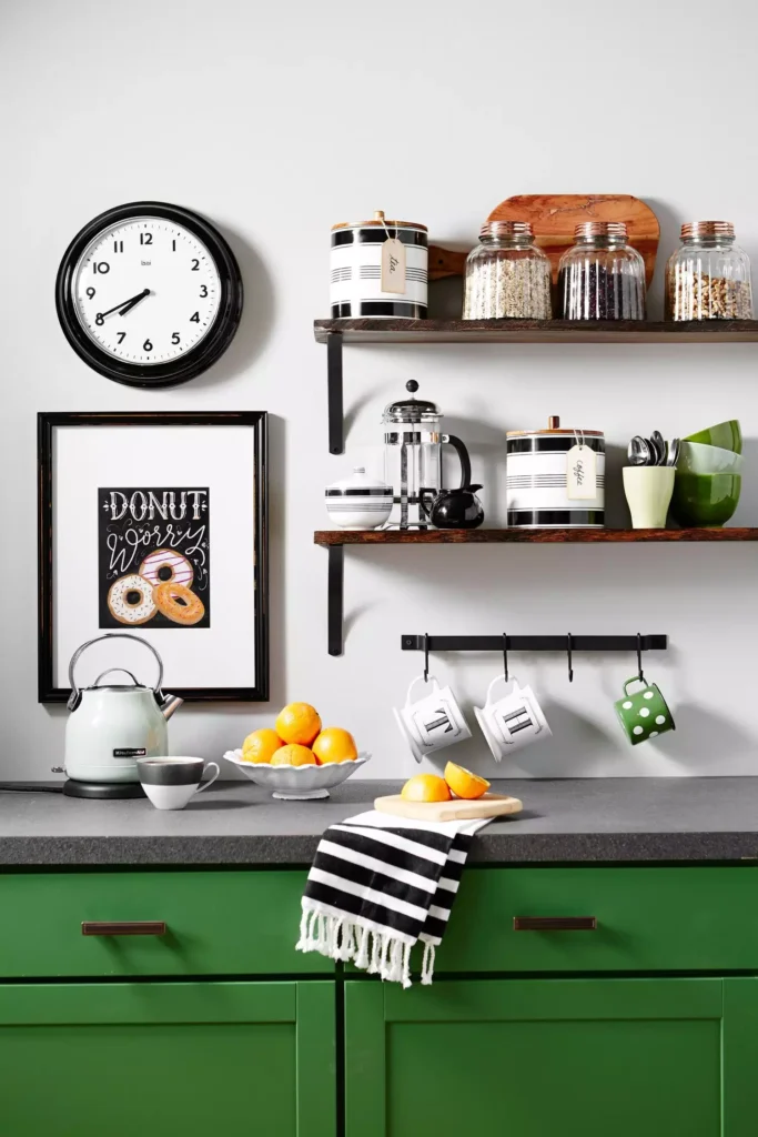 Donut Worry print, wall clock, and open shelves on a green cabinet kitchen wall