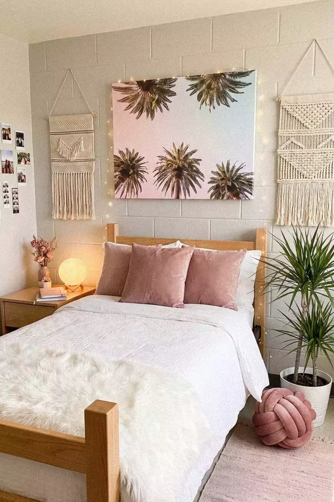 Dorm Wall Decor With A Palm Tree Canvas Between Two Macrame Wall Hangings Above A Blush Pink Dorm Bed