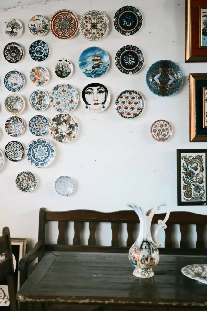 Eclectic plate wall decor with Ottoman-style, floral, and calligraphy patterns above a wooden bench