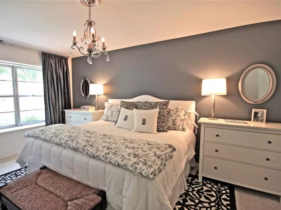 Elegant grey accent wall bedroom idea with white dresser, round mirror and floral bedding