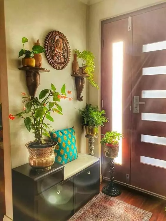 Entryway with Indian wall decor wooden elephant head shelf brackets, a carved Buddha panel, and potted plants