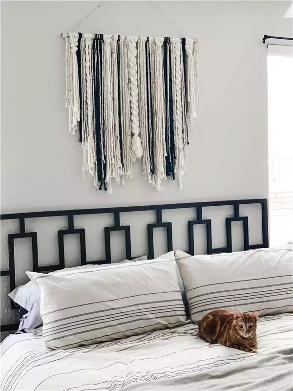 Fiber wall hanging in navy and cream as woven over the bed wall decor above a geometric headboard