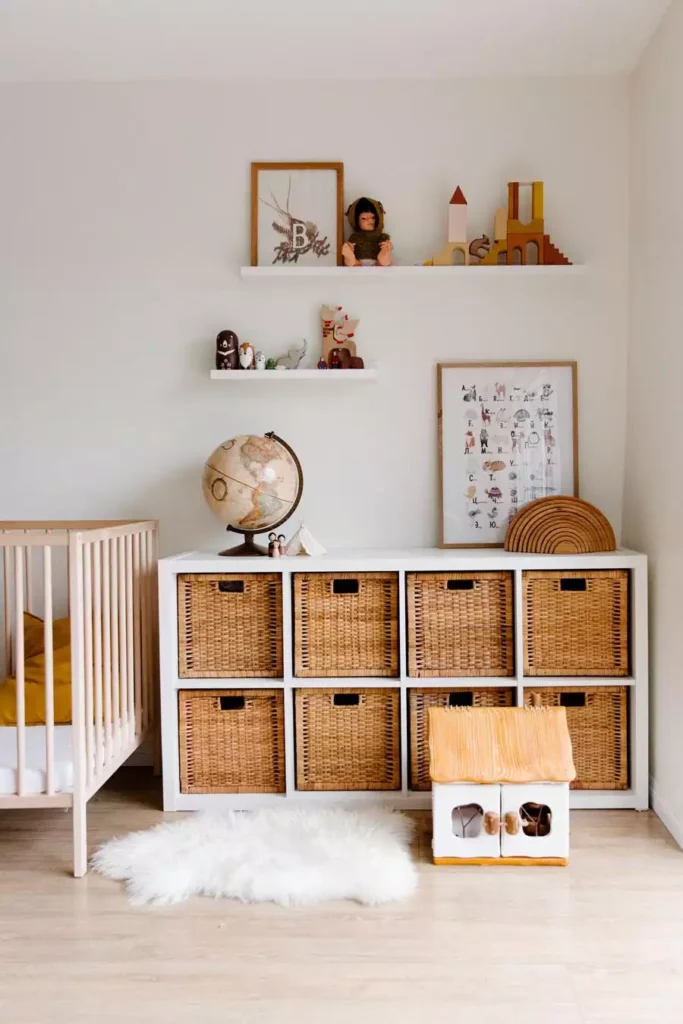 Floating shelves, an alphabet animal print and a framed botanical letter as neutral nursery wall decor above a wicker storage unit