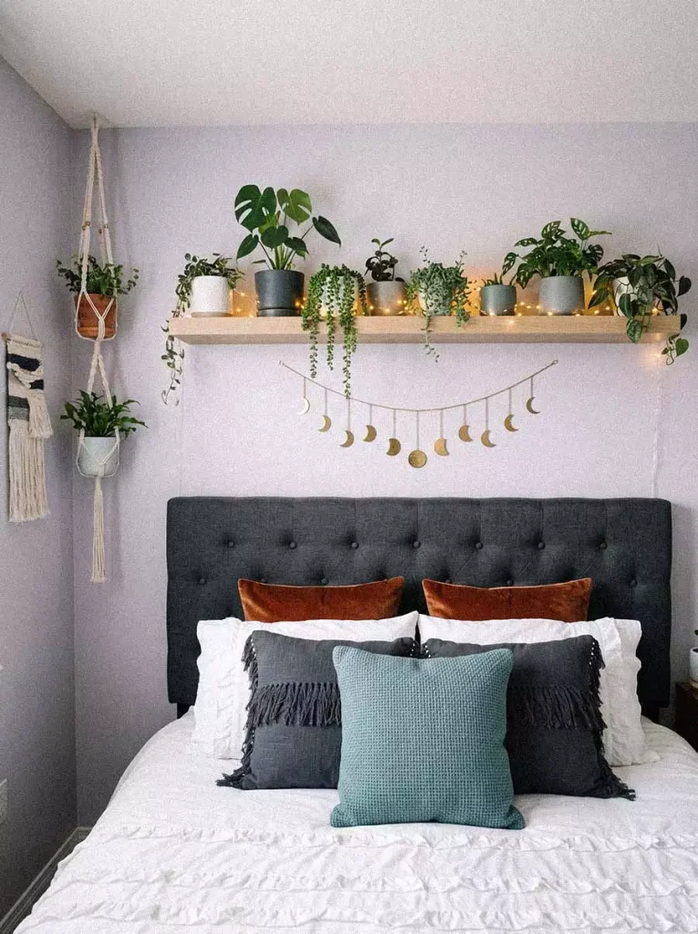 Floating Wood Shelf Decor With Trailing Plants Above A Tufted Headboard