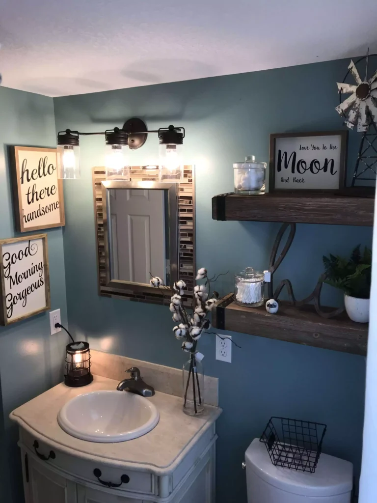 Framed typography signs and floating wood shelves in a teal bathroom