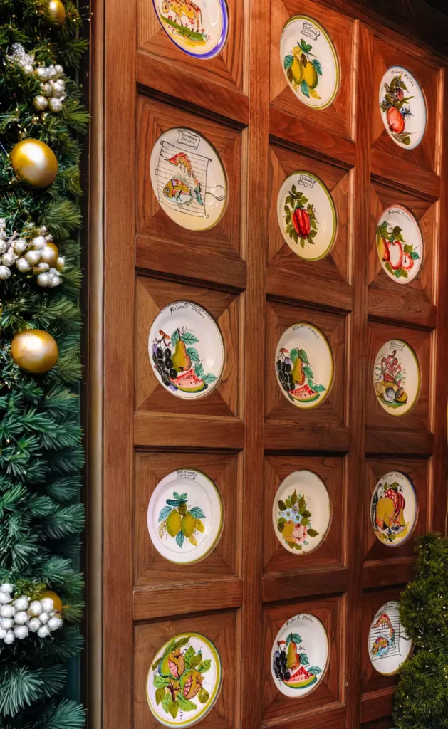 Fruit-themed plate wall decor mounted in wood paneled frames beside a Christmas garland