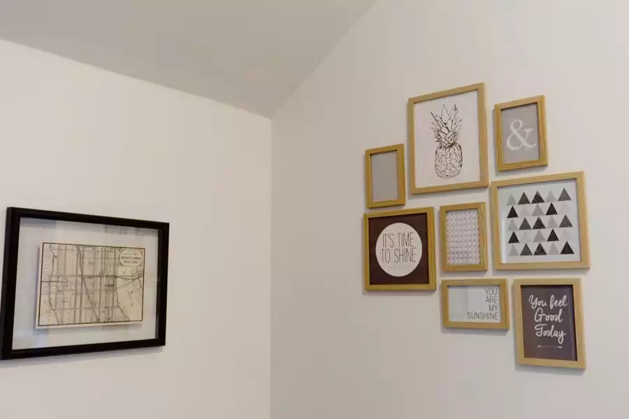 Gold Framed Prints And Quote Signs Arranged As Dorm Wall Decor On A Bright White Corner Wall