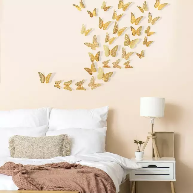 Golden 3D Butterfly Wall swirl drifting above a peach-toned bed nook