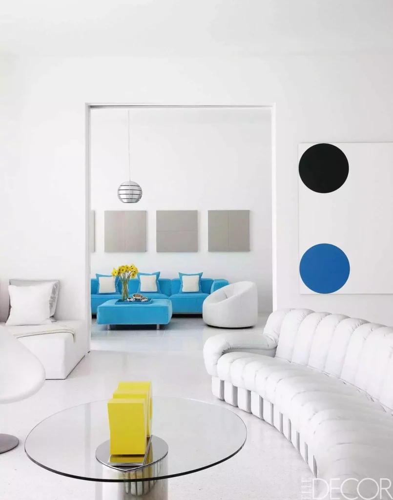 Graphic white walls, channel sofa, blue circle art, turquoise lounge beyond