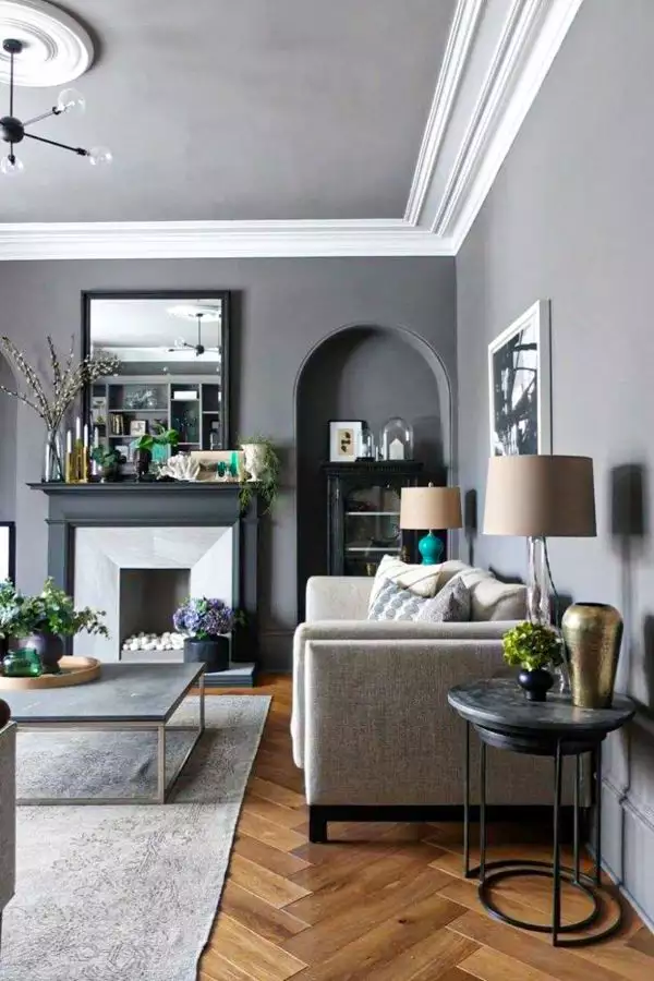 Grey living room with arched alcove, black mantel fireplace and herringbone wood floor