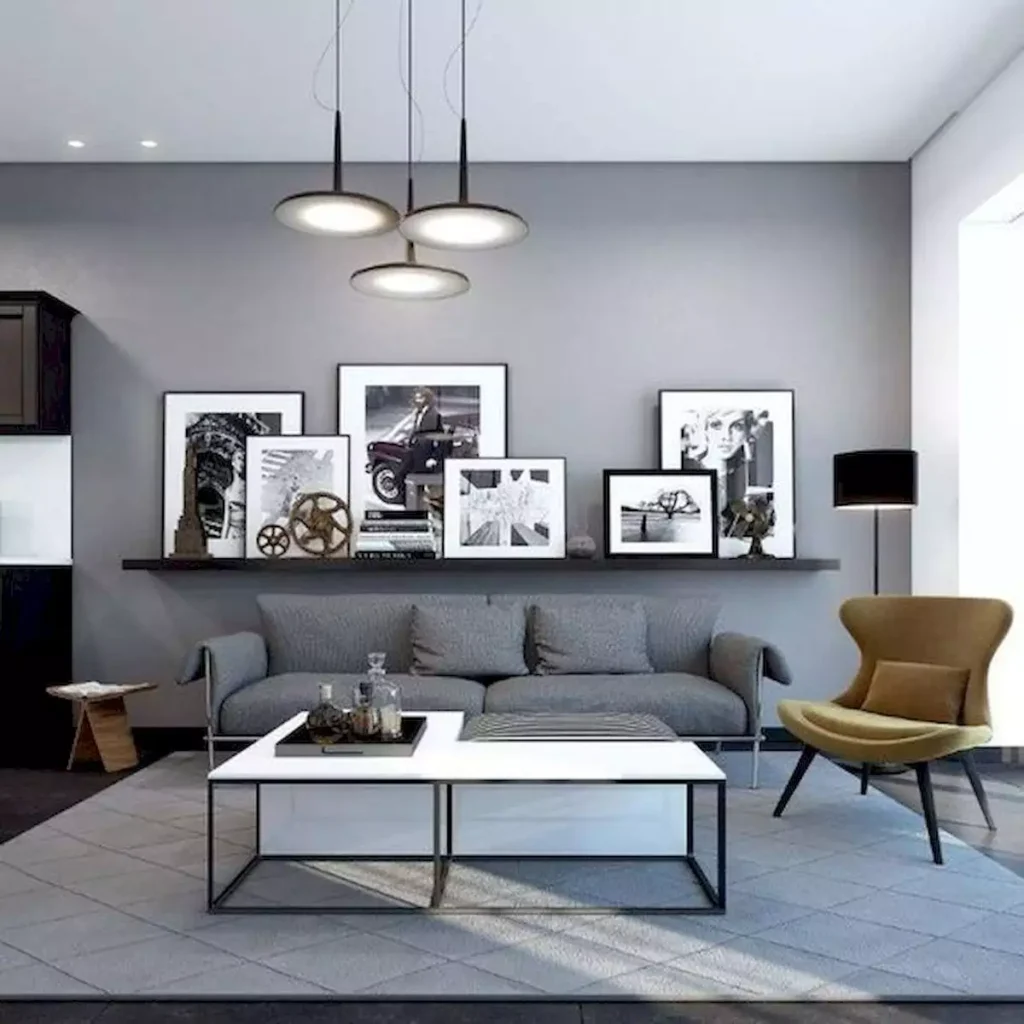 Grey wall living room styled with leaning gallery frames, mustard chair and pendant lights